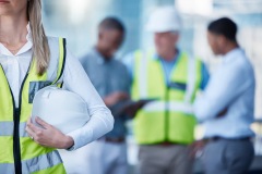 Architecture, planning and woman with helmet in blurred office for project management, teamwork and inspection. Civil engineering, collaboration and contractor at construction site with safety gear